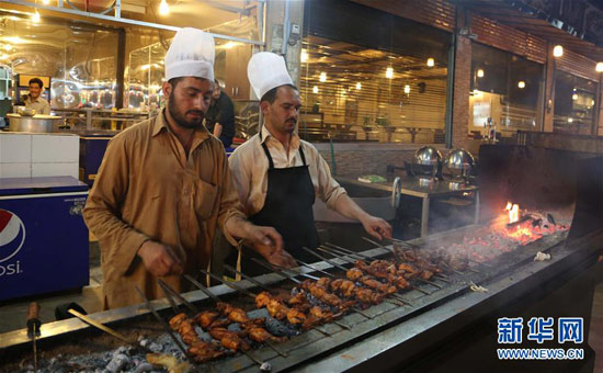 巴基斯坦拉瓦尔品第的一条美食街上，厨师在烤制鸡肉串和羊肉串。