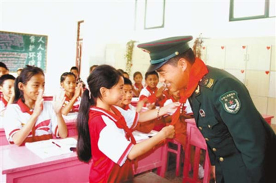 图为教师节来临之际，背崩乡中心小学学生代表德吉玉珍为周国仁系上红领巾，祝他节日快乐。 