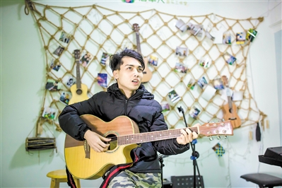 盲人乐手陈伟杰在工作室中弹吉他唱歌。 盲人乐手陈伟杰在工作室中弹吉他唱歌。