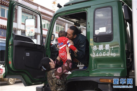 出发前，泽仁曲西将孙子举到丈夫其美多吉跟前，让祖孙俩告别（2017年8月28日）。新华社记者 吴光于 摄