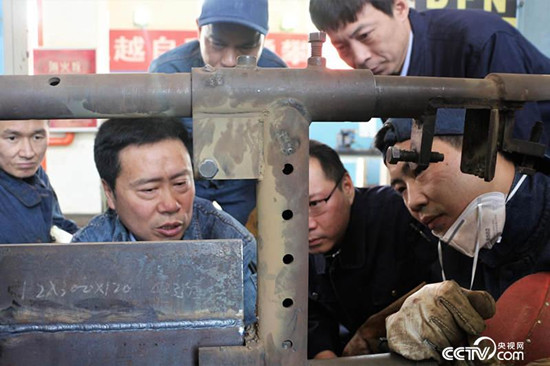 孔建伟(左二)和同事们在车间交流焊接技术。(记者何川/摄) 孔建伟(左二)和同事们在车间交流焊接技术。(记者何川/摄)