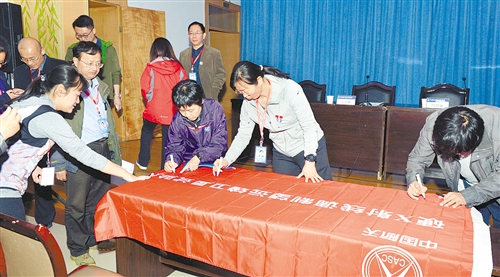 慧眼卫星团队成员在队旗上签名。 (资料图片) 慧眼卫星团队成员在队旗上签名。 (资料图片)