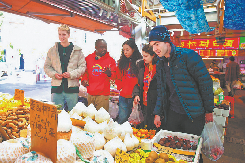 Vincent Aguesse (right) and several foreign guests visit a local farmers market in Kunming, Yunnan province, on Jan 20. CHINA DAILY
