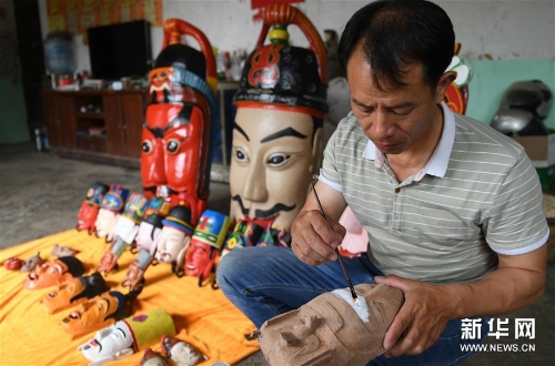 方文展在为一个毛南族傩面上涂料 方文展在为一个毛南族傩面上涂料