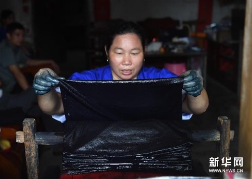 侗家妇女从染缸中取出染好的侗布