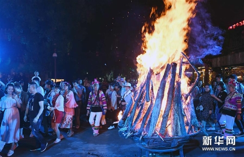 人们在云南楚雄彝人古镇火把节上狂欢