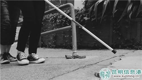 志愿者手持盲杖体验两点式探路法。