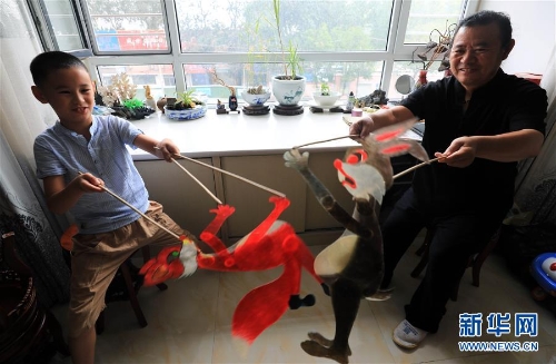 李卫与外孙一起表演皮影（7月11日摄）。