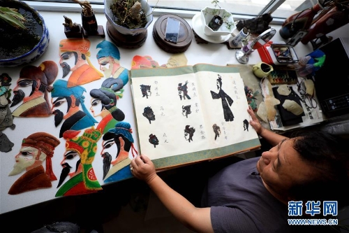 李卫展示自己制作的“济南名人脸谱”系列的皮影人偶。