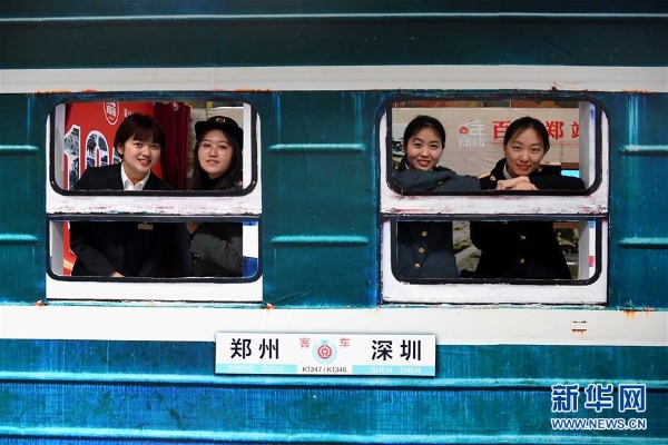 体验者穿着不同时期的铁路职工工作服在“绿皮车”造型展板前留影