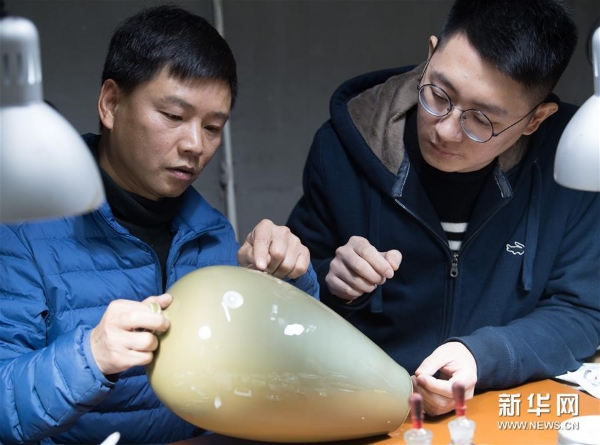 龙泉青瓷艺术家杨盛侃（右）将一件有瑕疵的作品带到吴荣强的工作室，跟他讨论漆缮修复的细节。