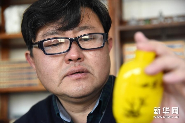 孙云毅在查看一只刚刚画完的鸡油黄鼻烟壶