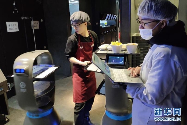 在北京海底捞智慧餐厅,员工(左)在后厨操控送菜机器人(1月30日手机拍摄)。 在北京海底捞智慧餐厅,员工(左)在后厨操控送菜机器人(1月30日手机拍摄)。
