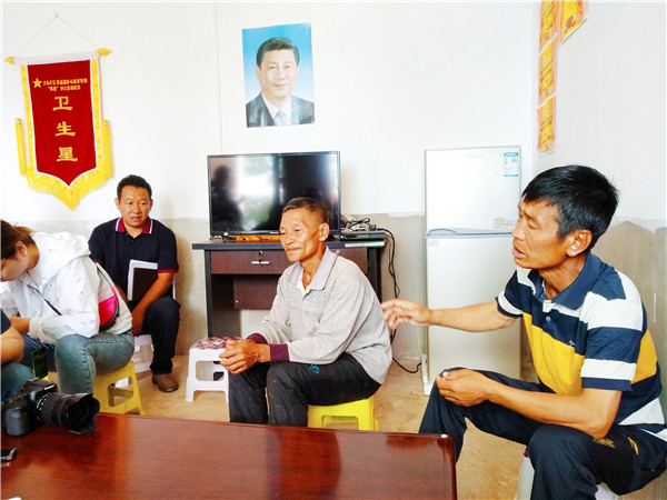 普初九（右一）在家里接受采访。记者江枫 摄