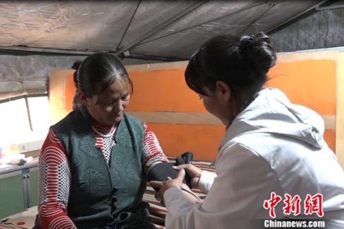 图为嘎宗卓玛正在给村民量血压。 图为嘎宗卓玛正在给村民量血压。