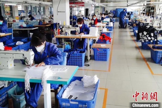 资料图：甘肃嘉峪关企业加班加点赶制纱布口罩和防护服。
