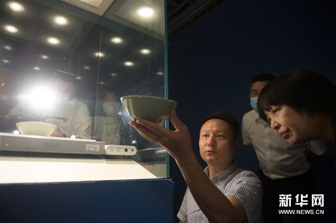 4刘杰（前左）在浙江省博物馆向陶瓷部主任沈琼华（前右）展示自己复刻的“马蝗绊”（5月15日摄）。 新华社记者 翁忻旸 摄