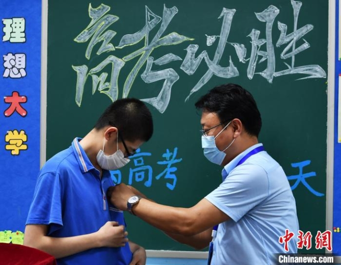 图为该中学校长为学生佩戴校徽。　翟羽佳 摄