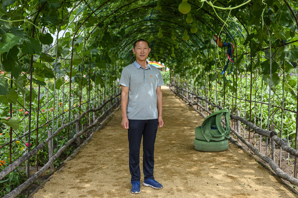 2020年8月,内蒙古兴安盟义勒力特嘎查,义勒力特嘎查党支部书记白双龙站在“开心果园”的葫芦藤下。