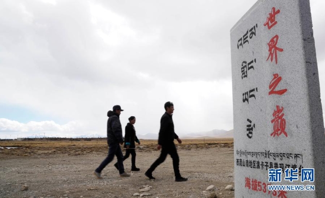 普玛江塘乡群众从“世界之巅”石碑前走过(4月16日摄)。 普玛江塘乡群众从“世界之巅”石碑前走过(4月16日摄)。