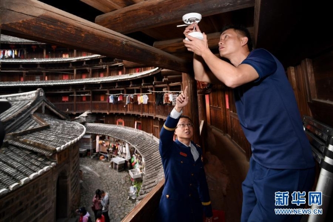 12月10日，福建省南靖县土楼景区专职消防队员（右）在土楼怀远楼内检查智能烟感探测器。