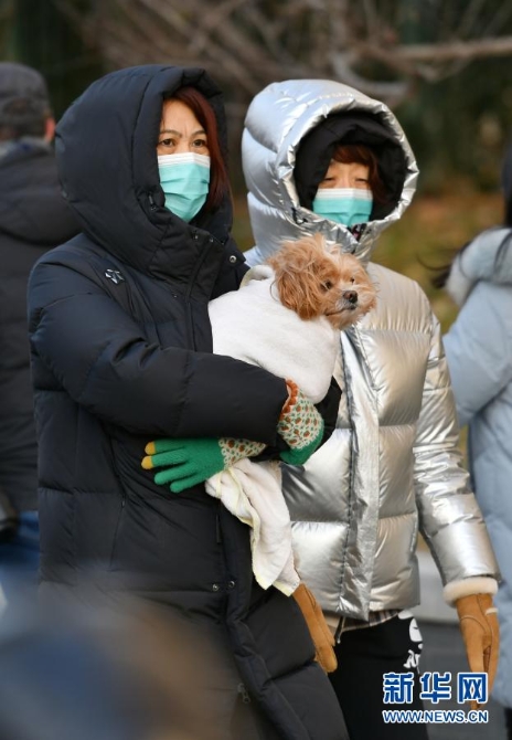 　12月29日，行人抱着宠物从北京宣武门路口走过。当日，入冬最强寒潮来袭，多地迎来今冬最寒冷天气。新华社记者 李鑫 摄