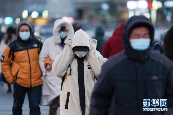 12月29日，一名行人捂着耳朵走过北京朝阳区青年路和朝阳北路路口。当日，入冬最强寒潮来袭，多地迎来今冬最寒冷天气。新华社记者鞠焕宗 摄