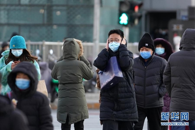 12月29日，一名行人捂着耳朵走过北京朝阳区青年路和朝阳北路路口。当日，入冬最强寒潮来袭，多地迎来今冬最寒冷天气。新华社记者鞠焕宗 摄1