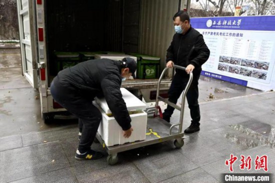 工作人员在风雪中运餐。　西安科技大学供图
