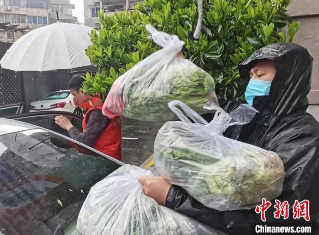 长宁区建宁居民区党总支书记马开骏(右)冒雨搬运物资 受访者供图 长宁区建宁居民区党总支书记马开骏(右)冒雨搬运物资 受访者供图