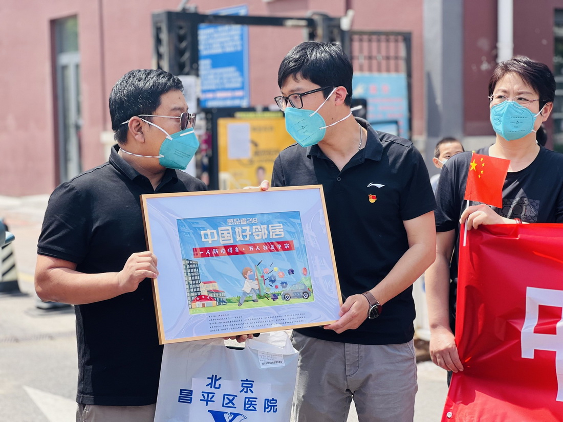 张旭（左一）康复后回到小区，收到了一幅主题为“中国好邻居”的手工艺品礼物（5月18日摄）。新华社发（周紫欣 摄）