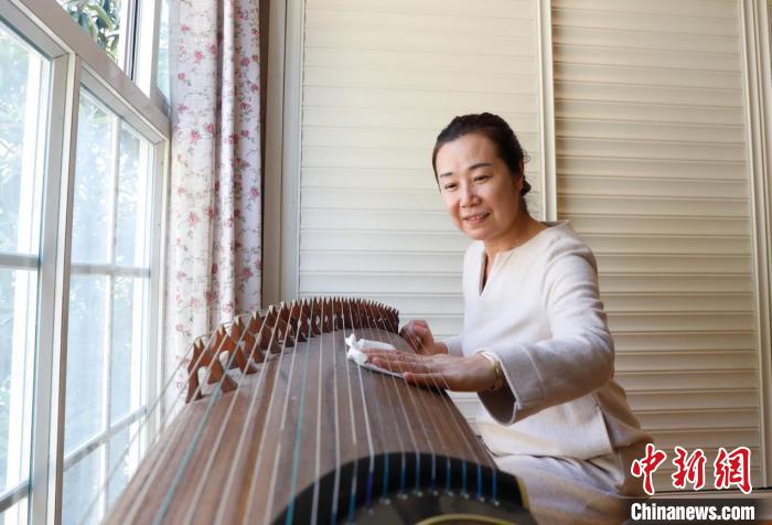 母亲李凤鸣正在擦拭庞钰千喜欢的古筝。　黎涛 摄