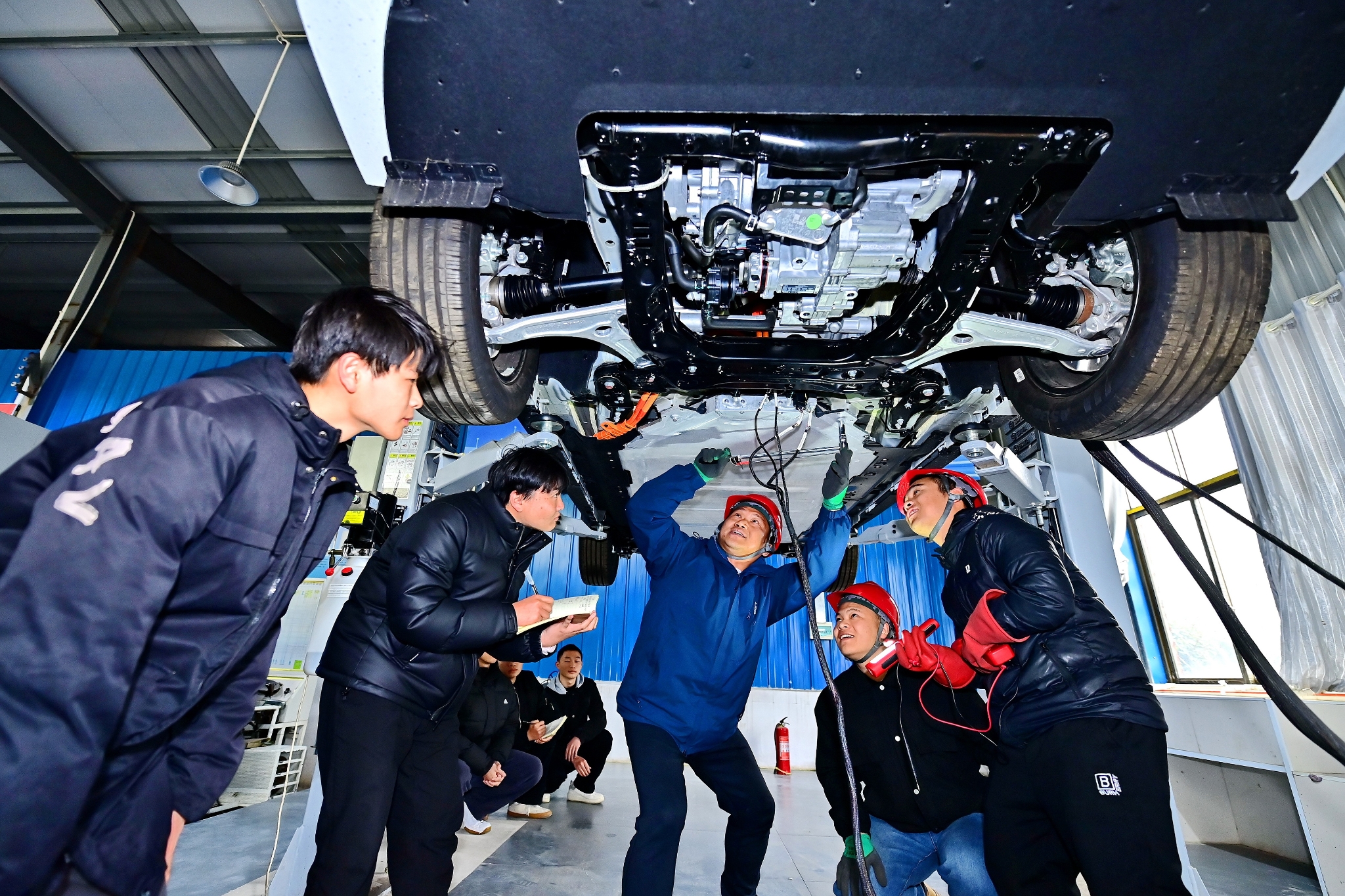2025年2月17日,江西省宜春市,丰城市的一所技工学校实训基地内,新能源汽车运维专业学生在老师的指导下学习新能源汽车电池包检修技术。