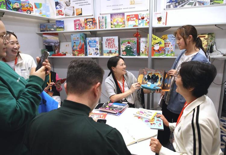 Exhibitors from China introduce a book to readers during the Eurasian Book Fair in Astana, Kazakhstan, April 23, 2025. (Photo by Kalizhan Ospanov/Xinhua)