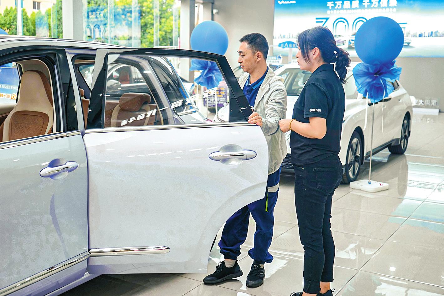 五菱汽车4S店销售员给顾客讲解车辆性能。