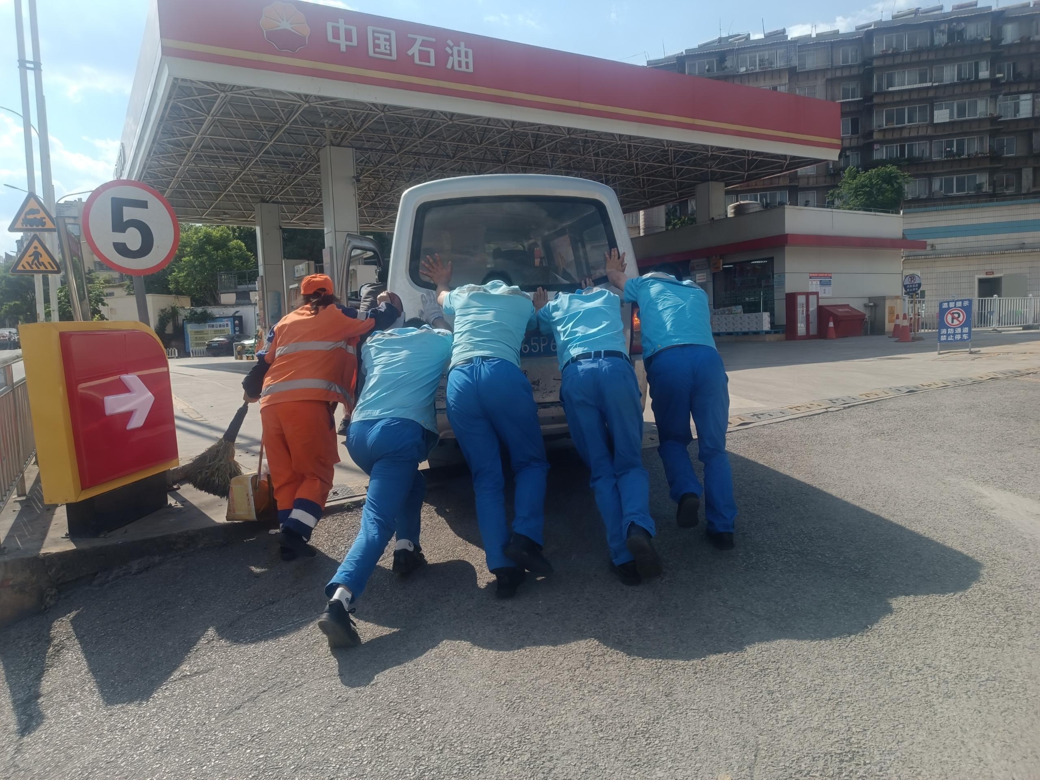 加油站员工和环卫工人帮忙为车辆抛锚顾客推车进站加油