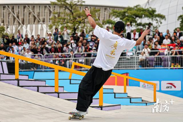 11月11日下午，十五运会滑板项目男子街式决赛，广东队潘家杰完成高难度动作后展开双臂与欢呼的观众们互动。郑新洽 摄