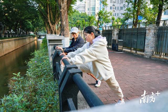 12月5日，在陪跑员李昀丰的指导下，许兴群做跑前拉伸。