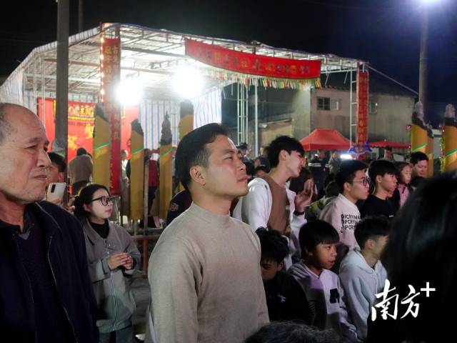 西都村党支部书记卢浩凯站在人群中默默观看演出，他是村里最早一批返乡办“村晚”的大学生。