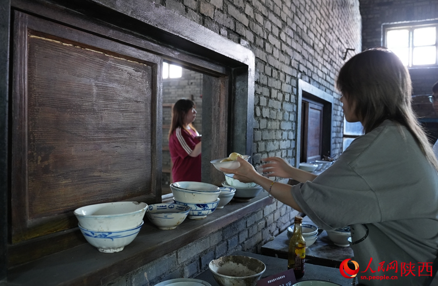 开局之年看中国|秦岭脚下的“时光片场” 游客沉浸式体验“打饭”场景。人民网记者 贾凯璐摄