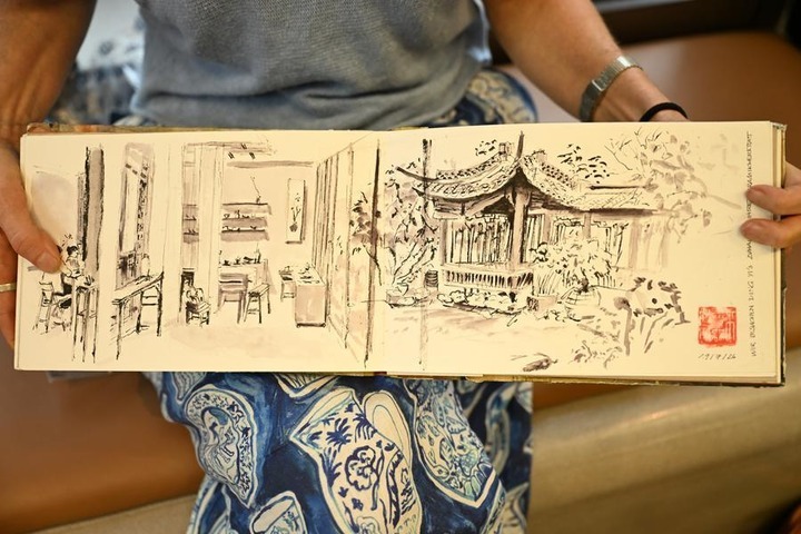 German art teacher Anke Deber shows a scenic picture she painted during her journey in China, in Hangzhou, east China's Zhejiang Province, July 21, 2026. (Xinhua/Liu Mingxiang)