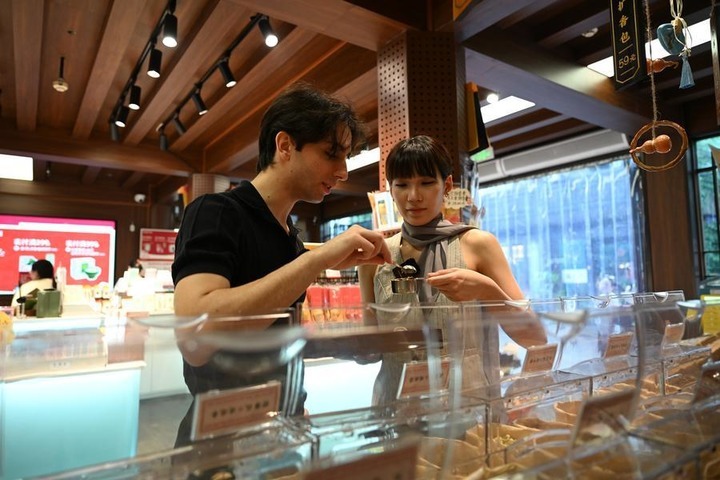 Italian vlogger Leonardo Lazzari (L) tries to make a herbal sachet in Gongshu District of Hangzhou, east China's Zhejiang Province, July 21, 2026. (Xinhua/Liu Mingxiang)
