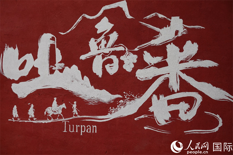 一幅绘有吐鲁番及其中文名“吐鲁番”的壁画,以及中国古典名著《西游记》中发生在吐鲁番的著名场景。人民网记者 王禹蘅摄