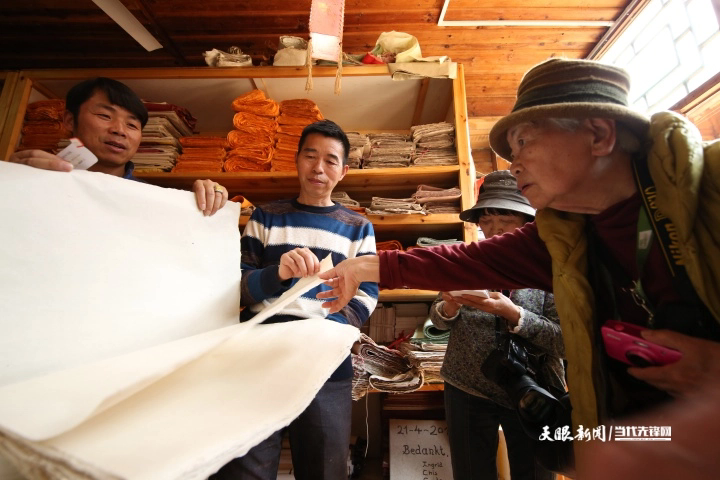 贵州省丹寨县南皋乡石桥村手工皮纸展示馆，王兴武（左二）在向日本游客介绍新式白皮纸的质量。.JPG