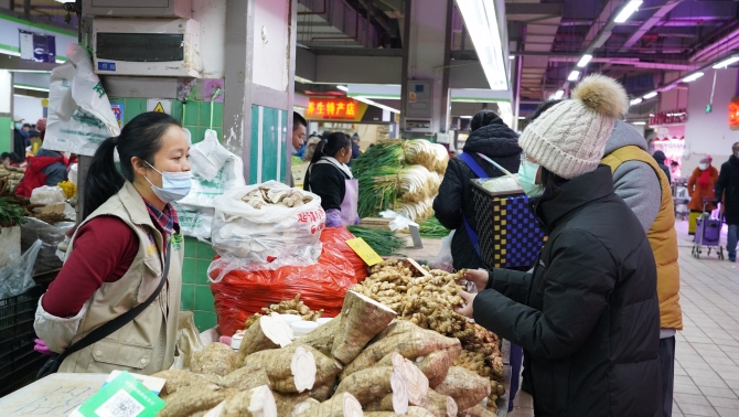 居民在摊位前买菜